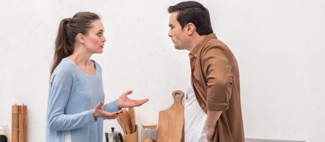 side view of adult couple having quarrel at kitchen